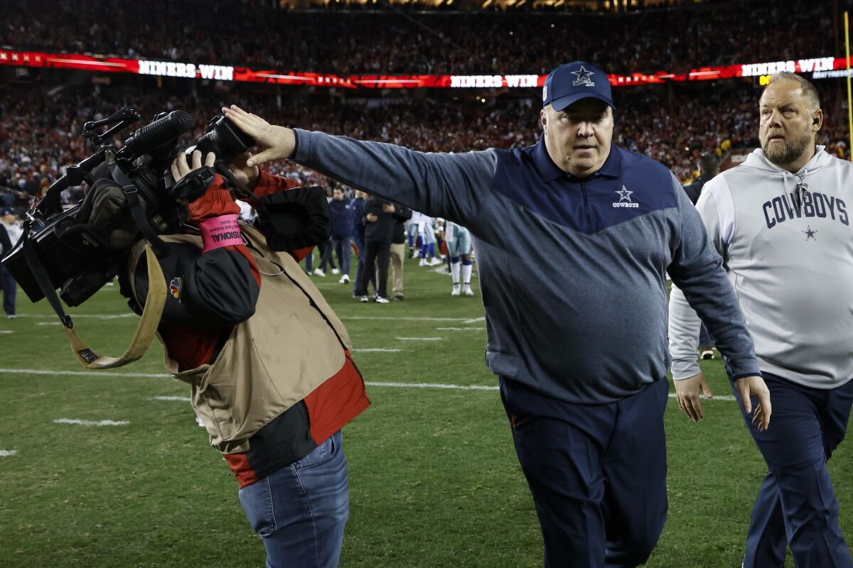 Dallas Cowboys head coach Mike McCarthy appears to push a camera operator away while walking off the field.