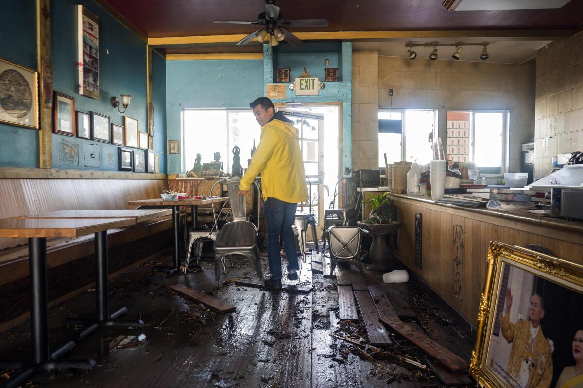 A restaurant owner surveys storm damage.
