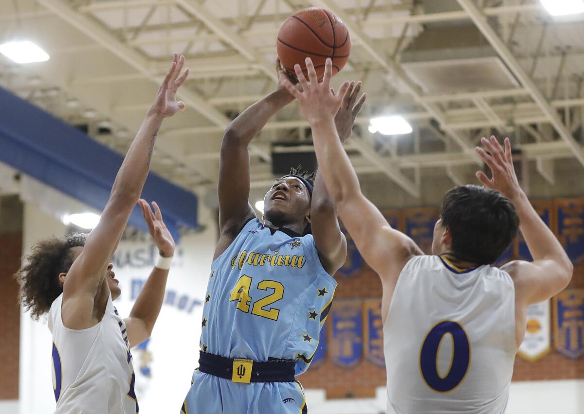 Marina's AJ Robinson (42) puts up a floater between two Fountain Valley defenders for a basket on Friday night.