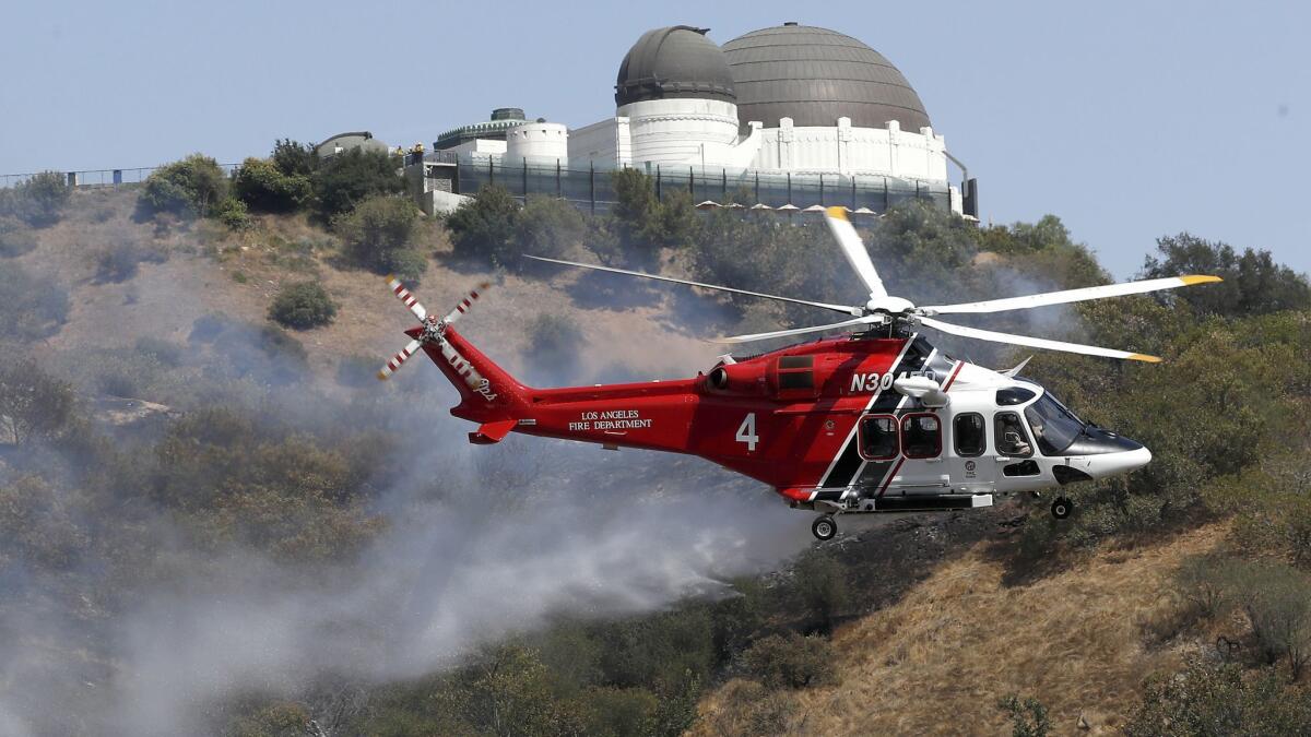 A Los Angeles City Fire Department heliciopter drops water on a brush fire near the Griffith Observatory.