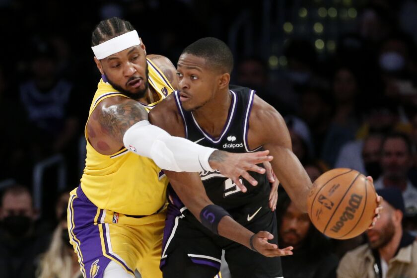 Los Angeles Lakers forward Carmelo Anthony, left, defends against Sacramento Kings guard De'Aaron Fox (5) during the first half of an NBA basketball game in Los Angeles, Friday, Nov. 26, 2021. (AP Photo/Ringo H.W. Chiu)