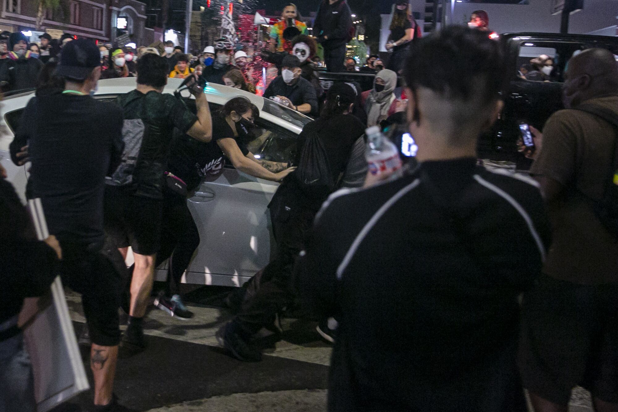 A Prius runs through a crowd of people on Sunset Boulevard and North Cahuenga Boulevard during a protest Thursday.