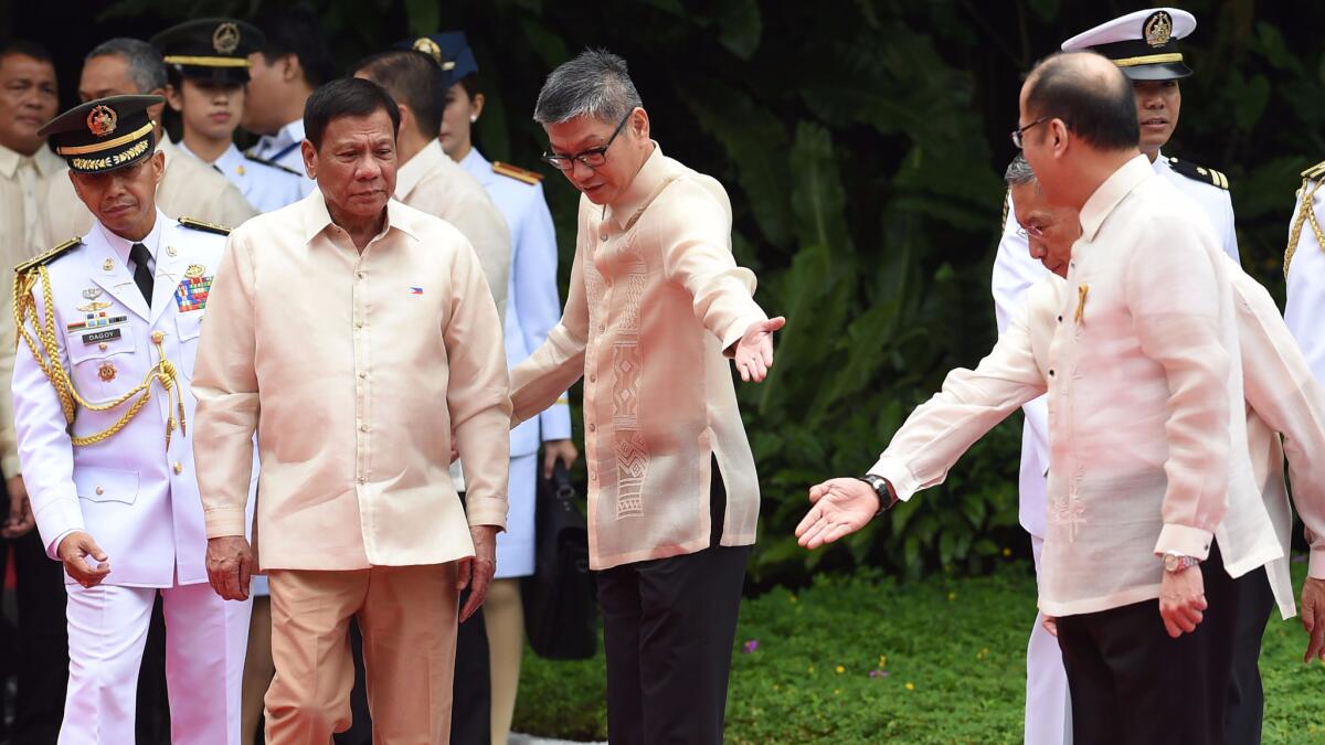 Incoming Philippines President Rodrigo Duterte, left, is led by government officials while outgoing president Benigno Aquino, right, looks on prior to a departure ceremony for Aquino at the Malacanang Palace in Manila on June 30.