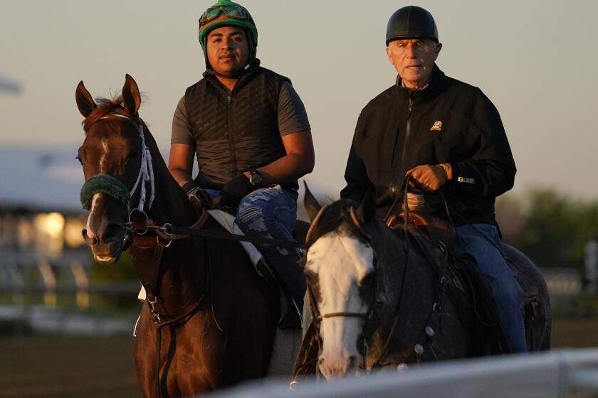 Horse trainer D. Wayne Lukas, right, rides atop Riff as he helps exercise rider Oscar Quevedo and Secret Oath off the track