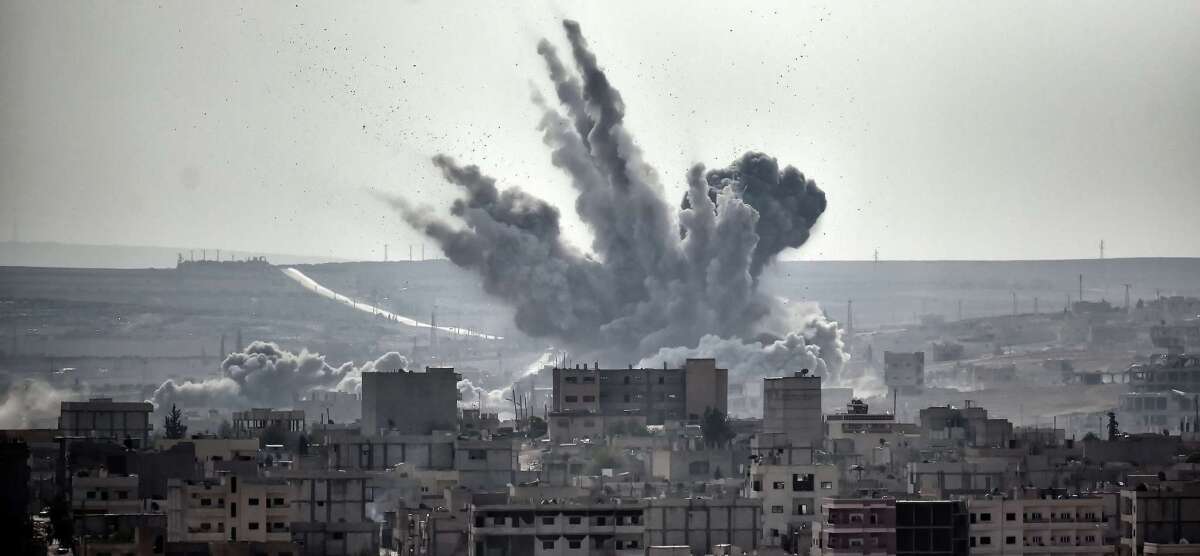 A shell can be seen exploding Nov. 13 in the Syrian city of Kobane from the Turkish border village of Mursitpinar.