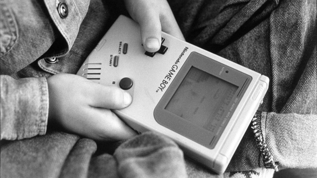 A boy plays on a Nintendo Game Boy.