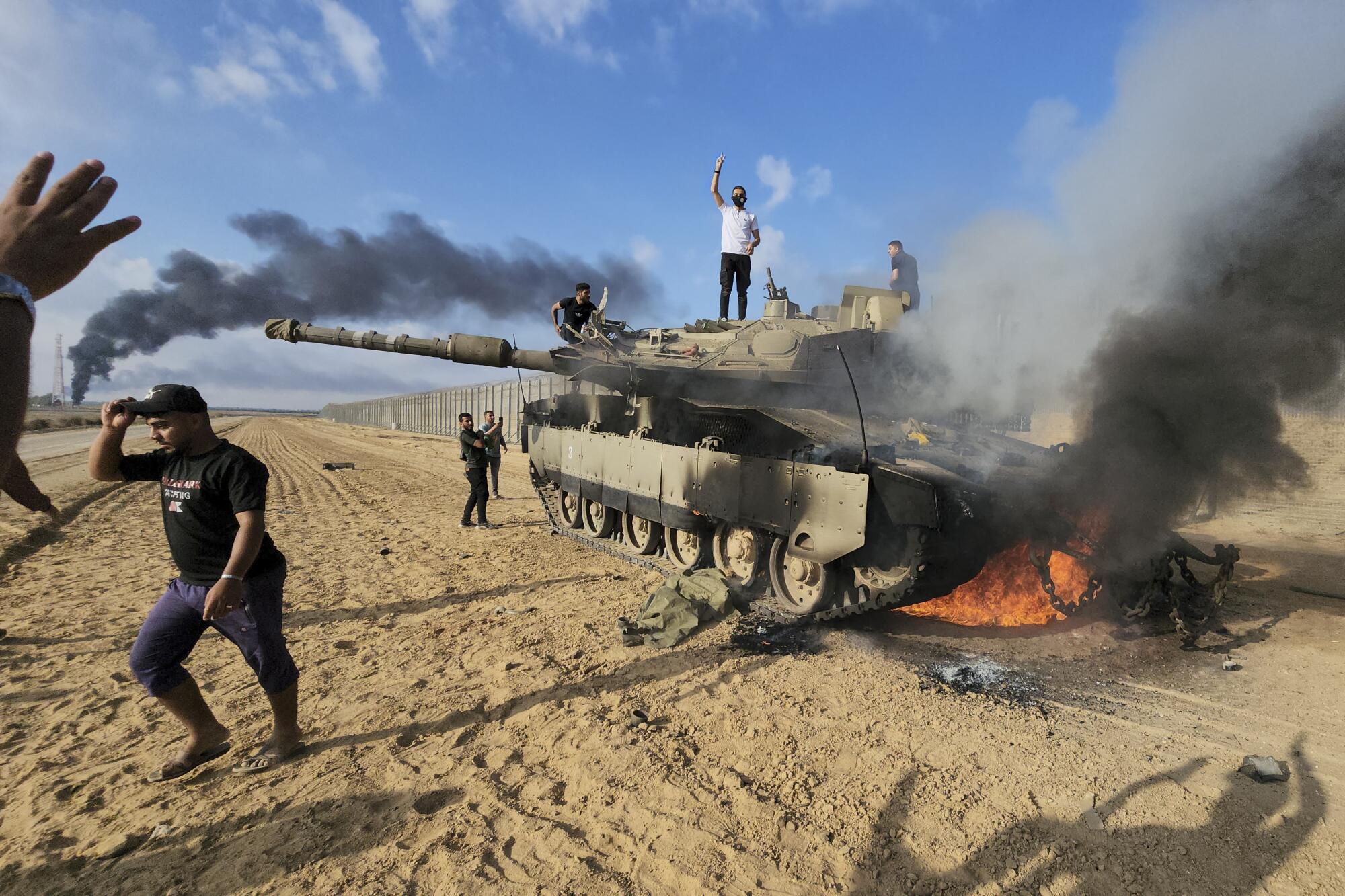 Palestinians celebrate near an Israeli tank.