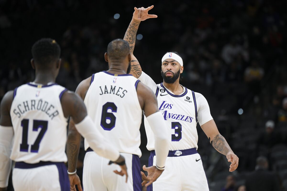 Anthony Davis (3) of the Lakers celebrates with LeBron James and Dennis Schroder on November 25, 2022.