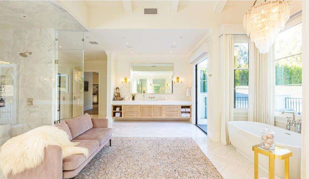 The primary bathroom with seating and windows overlooking the grounds.