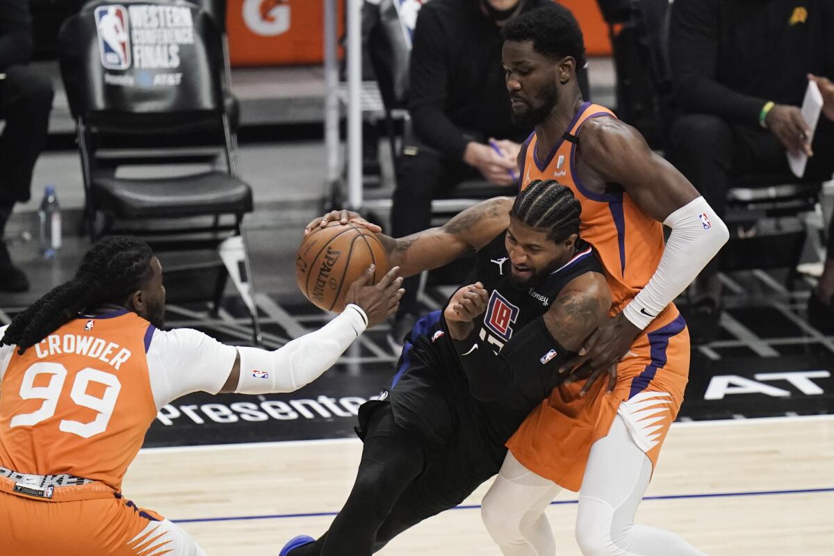 Clippers guard Paul George tries to drive between Phoenix's Jae Crowder and Deandre Ayton.