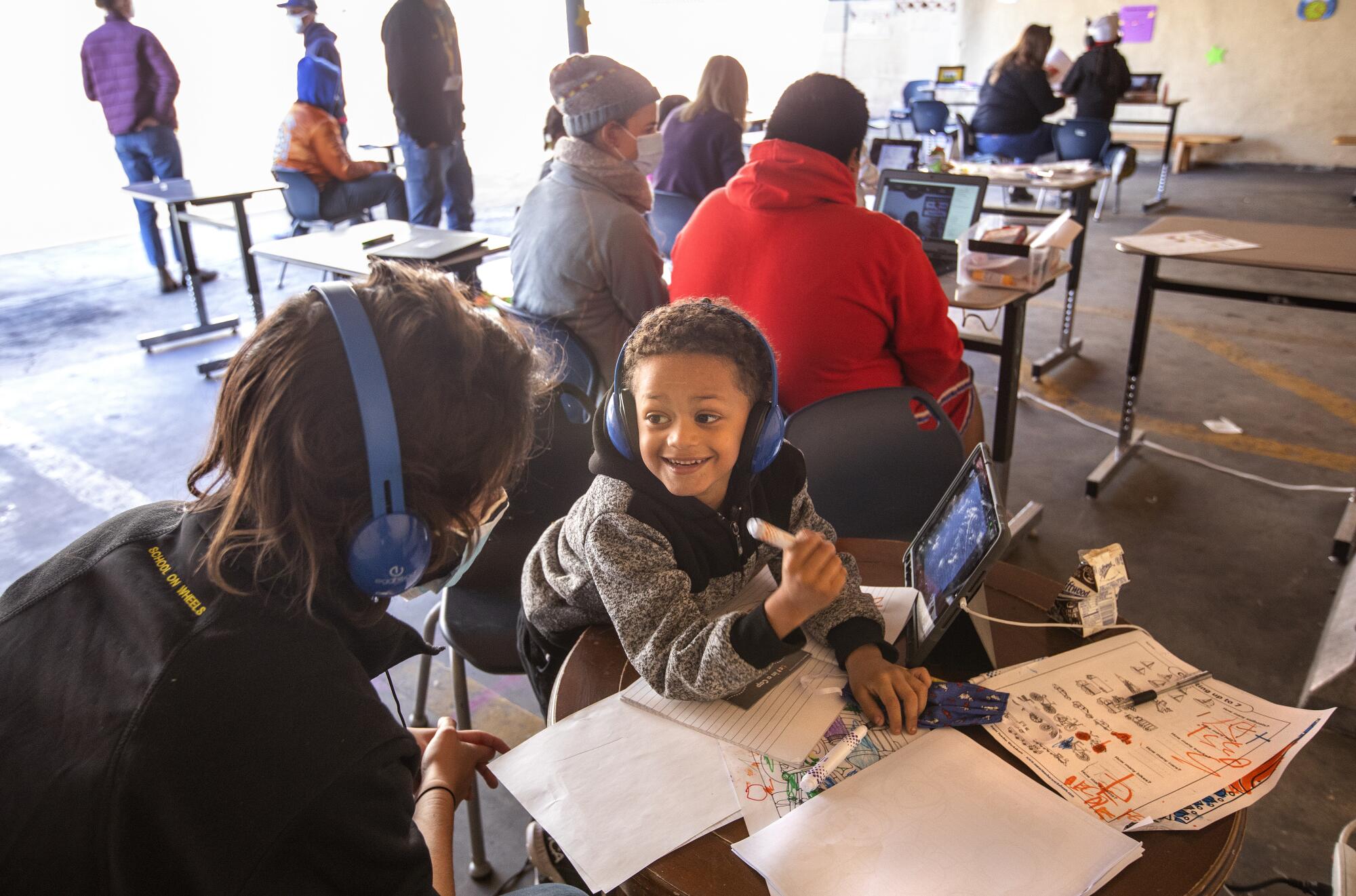 Emma Gerch helps kindergartner learn to read and write at a learning pod for homeless children at the Hyland Motel