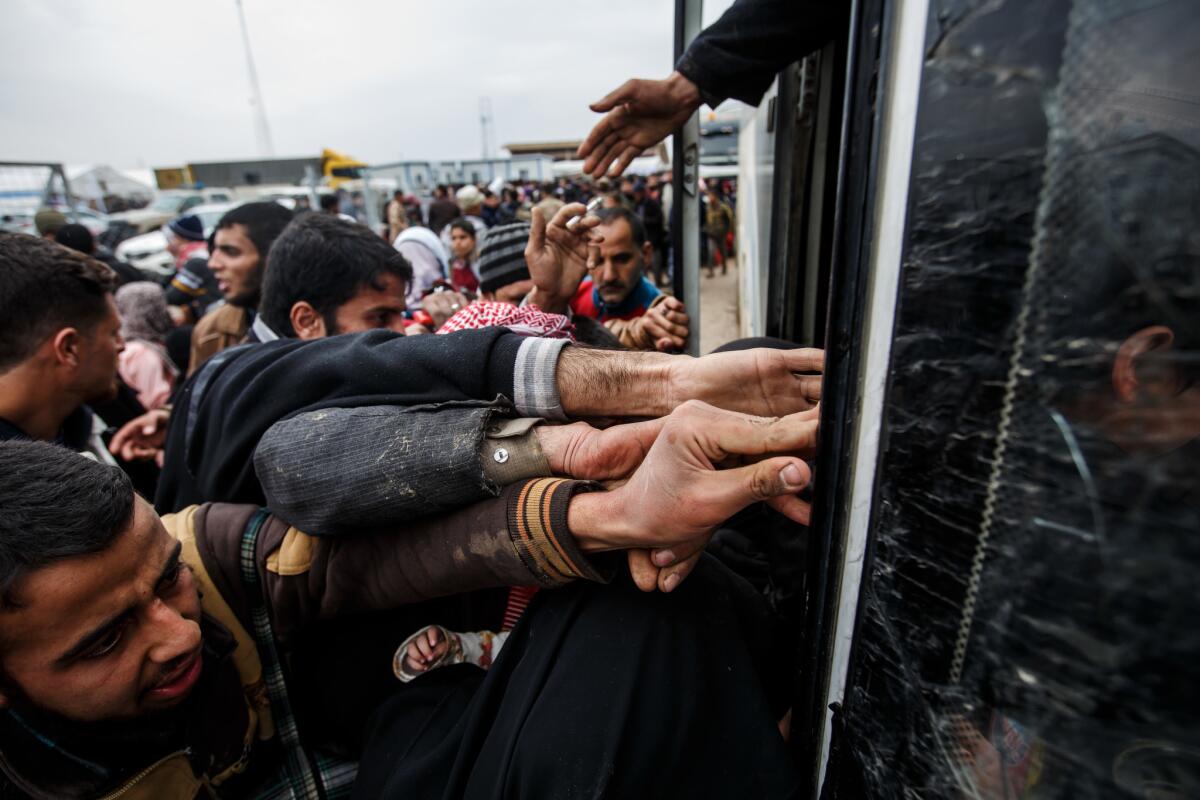 Civilians fleeing Mosul try to push their way onto a bus headed for another displaced persons camp March 23 outside Hammam Alil, Nineveh province.