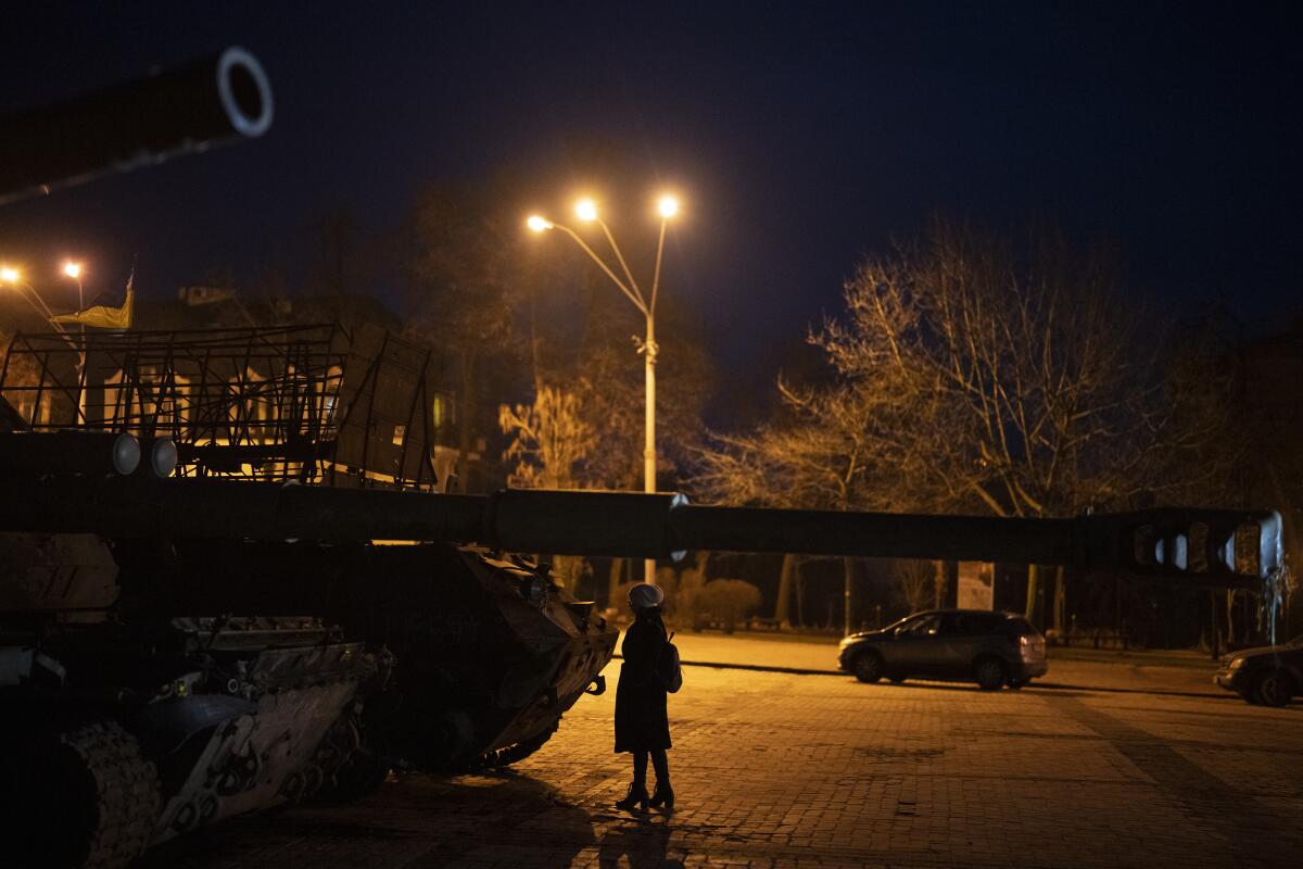 Una mujer parada frente a vehículos blindados y tanques rusos destruidos en el centro de Kiev, Ucrania,