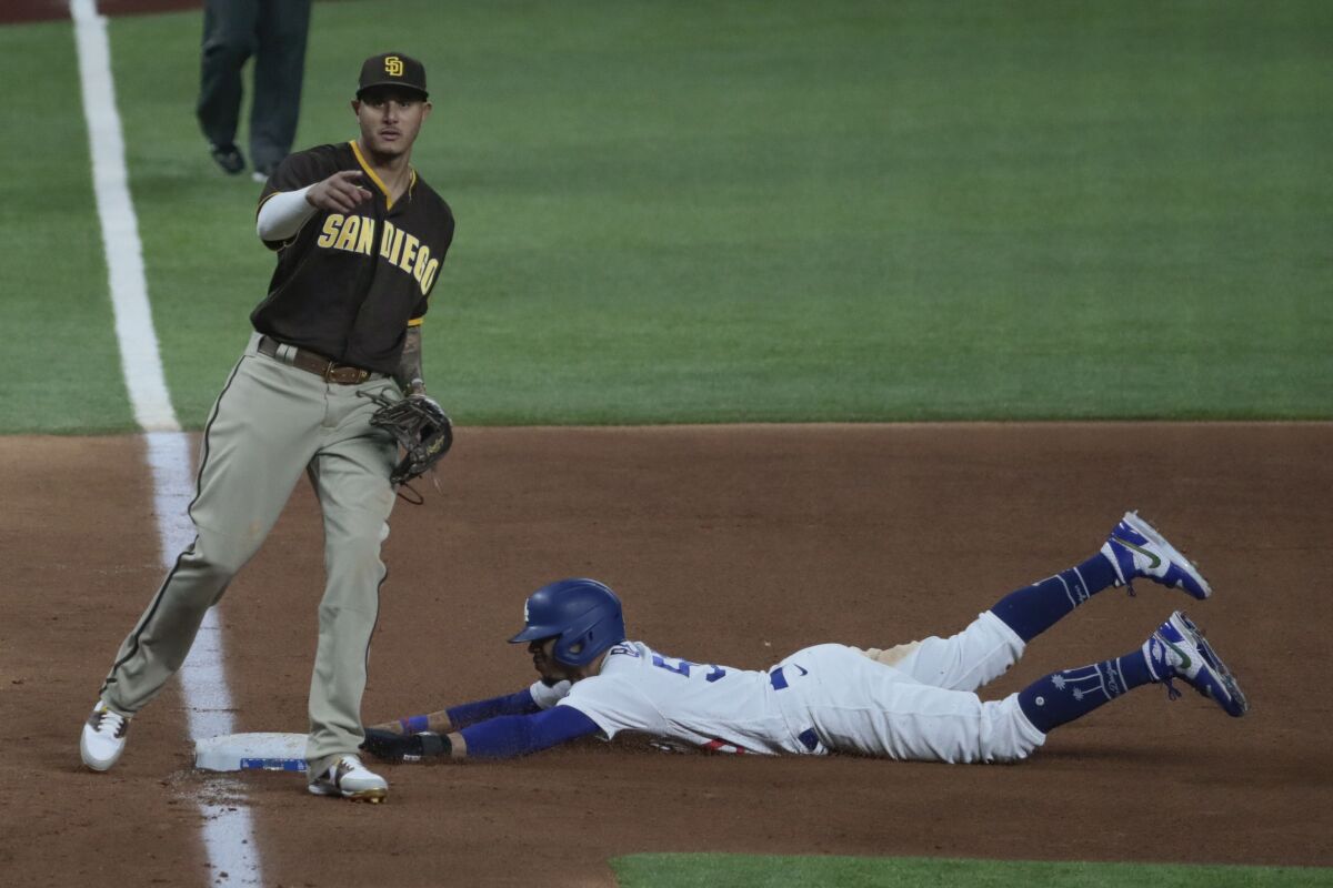 Dodgers right fielder Mookie Betts slides into third behind Padres' Manny Machado as part of a double steal 