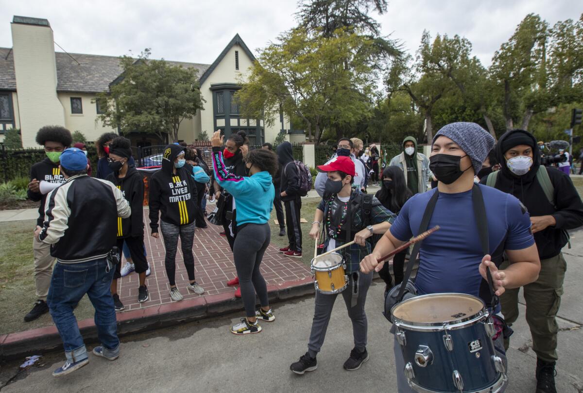 People congregate, two playing drums, outside the Getty House. 