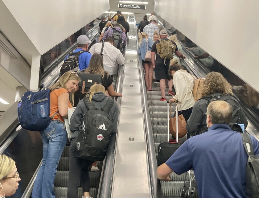 Travelers ascend an escalator to a concourse at Hartsfield-Atlanta International Airport on Thursday, June 30, 2022 in Atlanta. (AP Photo/Jay Reeves)