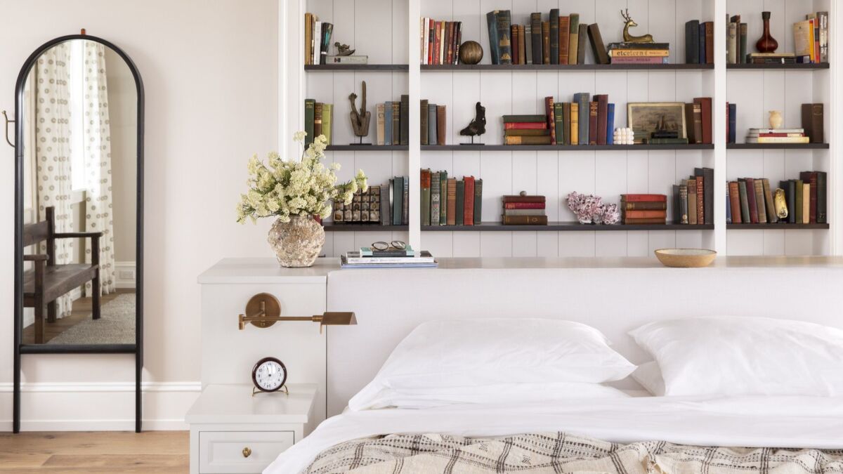 In a neutral bedroom in Nantucket designed by Martinez, a built-in bookcase doubles as a headboard and serves as the room's source of color and texture.