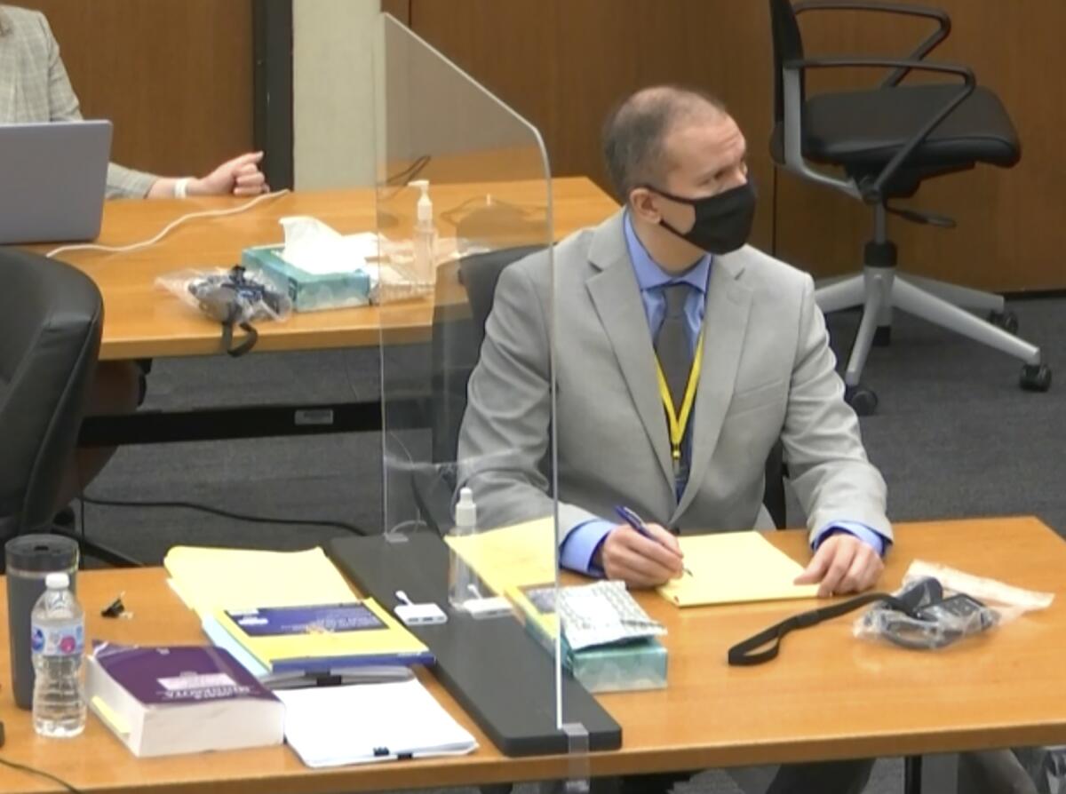 Derek Chauvin sits at a table in court