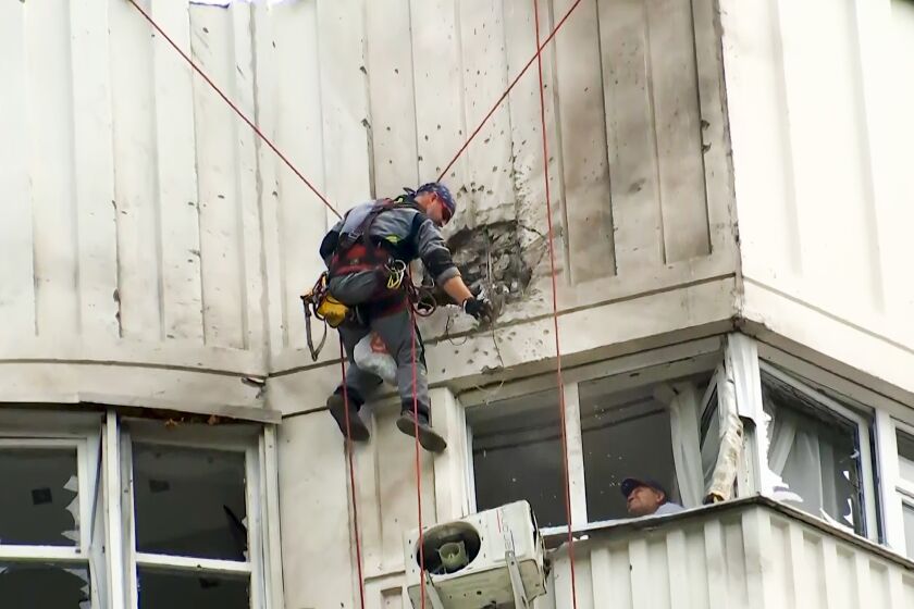 In this image taken from video, investigators inspect the building after a Ukrainian drone damaged an apartment building in Moscow, Russia, Tuesday, May 30, 2023. In Moscow, residents reported hearing explosions and Mayor Sergei Sobyanin later confirmed there had been a drone attack that he said caused "insignificant" damage. (AP Photo)