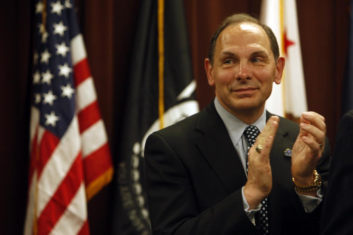 Secretary of Veterans Affairs Robert McDonald applauds at the VA's West Los Angeles health campus after announcing his efforts to end homelessness among veterans in the county.