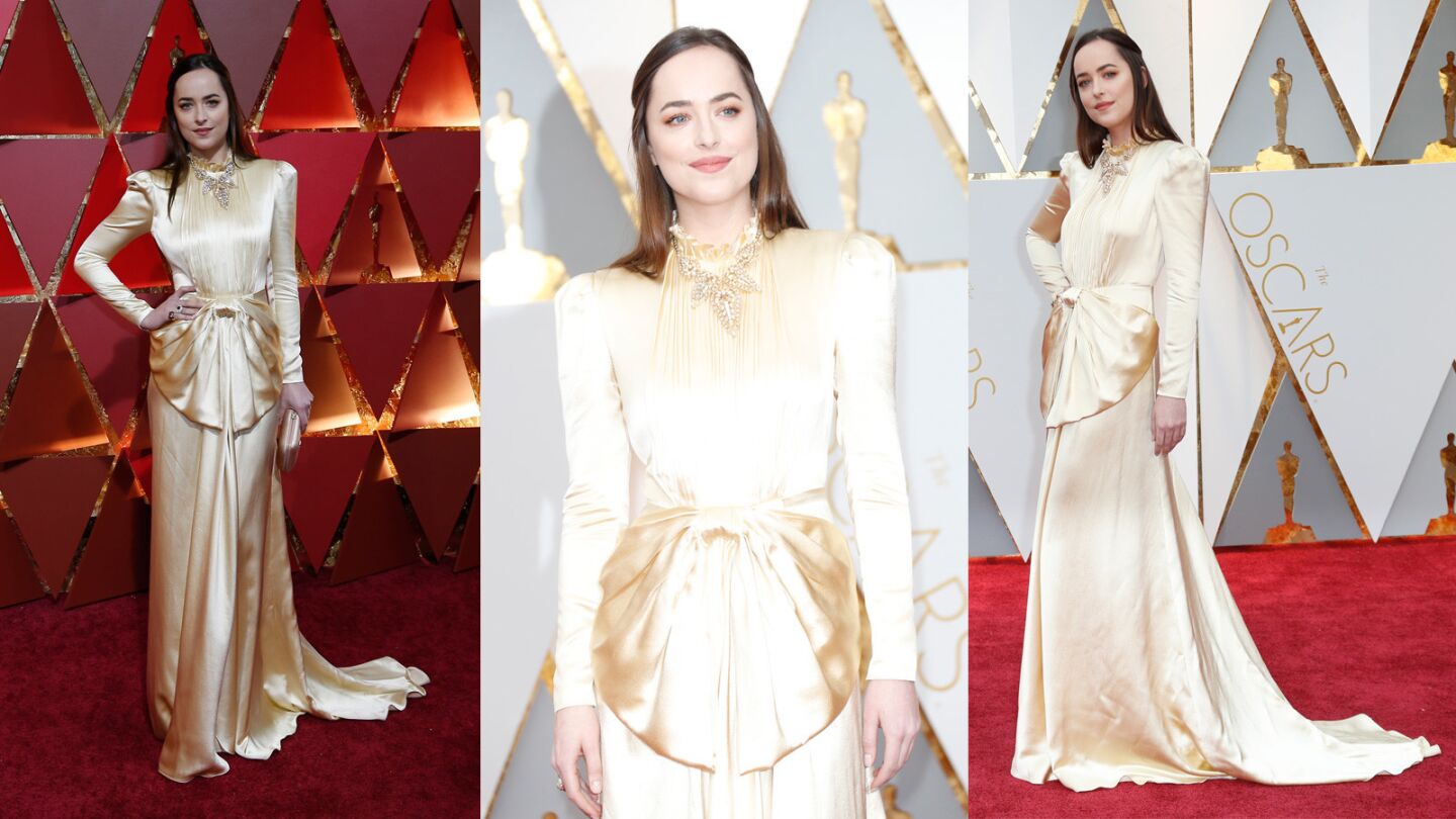 Dakota Johnson is wearing a Gucci champagne satin long-sleeve, high-neck gown with metallic gold high heel shoes and metallic gold clutch. She looks as though she was trying to be a life-sized replica of the golden Oscar statuettes. Dressing like the award was not a winning move and therefore scored her a place on our worst-dressed list.