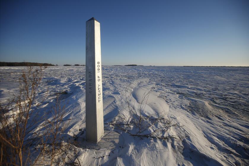 A border marker, between the United States and Canada is shown just outside of Emerson, Manitoba, on Thursday, Jan. 20, 2022. A Florida man was charged Thursday with human smuggling after the bodies of four people, including a baby and a teen, were found in Canada near the U.S. border, in what authorities believe was a failed crossing attempt during a freezing blizzard. The bodies were found Wednesday in the province of Manitoba just meters (yards) from the U.S. border near the community of Emerson. (John Woods/The Canadian Press via AP)