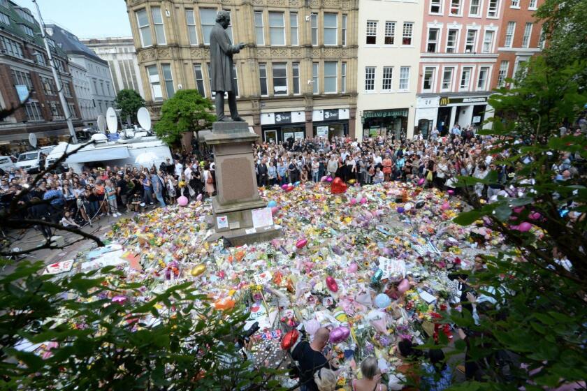 People hold a minute of silence in a square in central Manchester, England, Thursday, May 25, 2017, for the victims of the suicide attack at an Ariana Grande concert that left more than 20 people dead and many more injured, as it ended on Monday night at the Manchester Arena. (Ben Birchall/PA via AP)