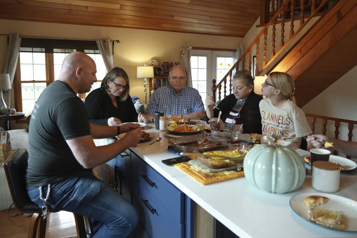 Doug Whitney (centro) desayuna con su familia en Manson, Washington, el 5 de noviembre de 2022. Whitney heredó la misma mutación genética que hizo que le diera alzhéimer a su madre, hermano y otros parientes durante varias generaciones, a la edad inusualmente joven de 50 años. Doug tiene 73 años y aún tiene una mente aguda. De alguna manera, evadió su destino genético. (AP Foto/Shelby Lum)