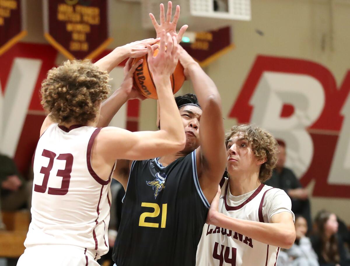 Marina's Jared Palacio (21) tries to break through the defense of Dylan McEachern (33) and Sam Burchi (44) for a lay-up.