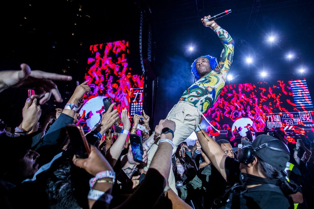 Lil Uzi Vert performs in the middle of the crowd with brightly colored screens behind him