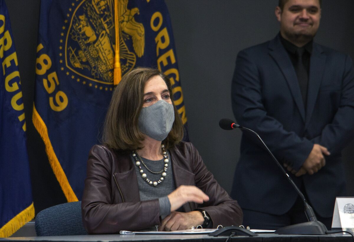 Oregon Gov. Kate Brown wears a mask while attending a news conference in November