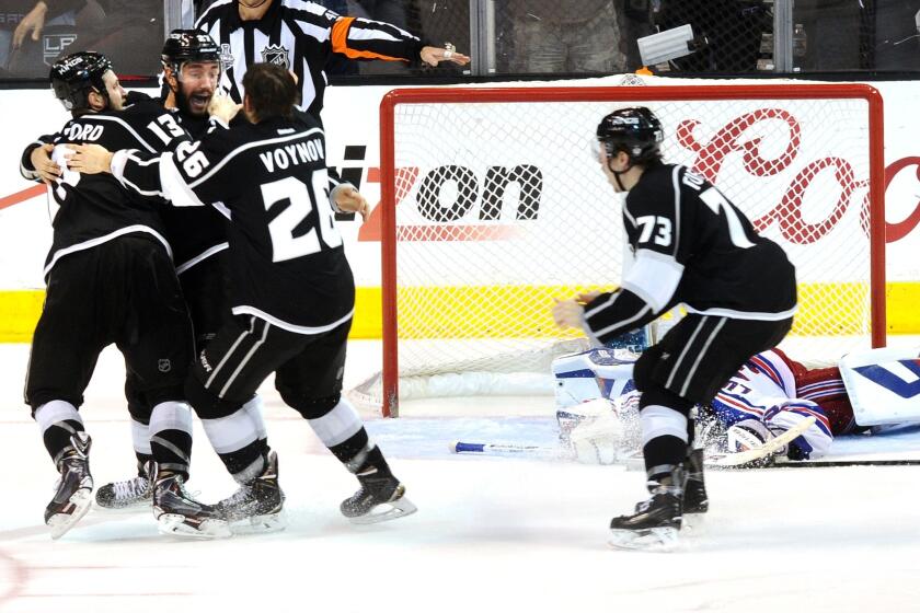 Kings teammates Kyle Clifford (13) and Slava Voynov (26) embrace defensemen Alec Martinez and Tyler Toffoli (73) prepares to join in after Martinez scored the winning goal against the Rangers to end Game 5 of the Stanley Cup Final in double overtime.