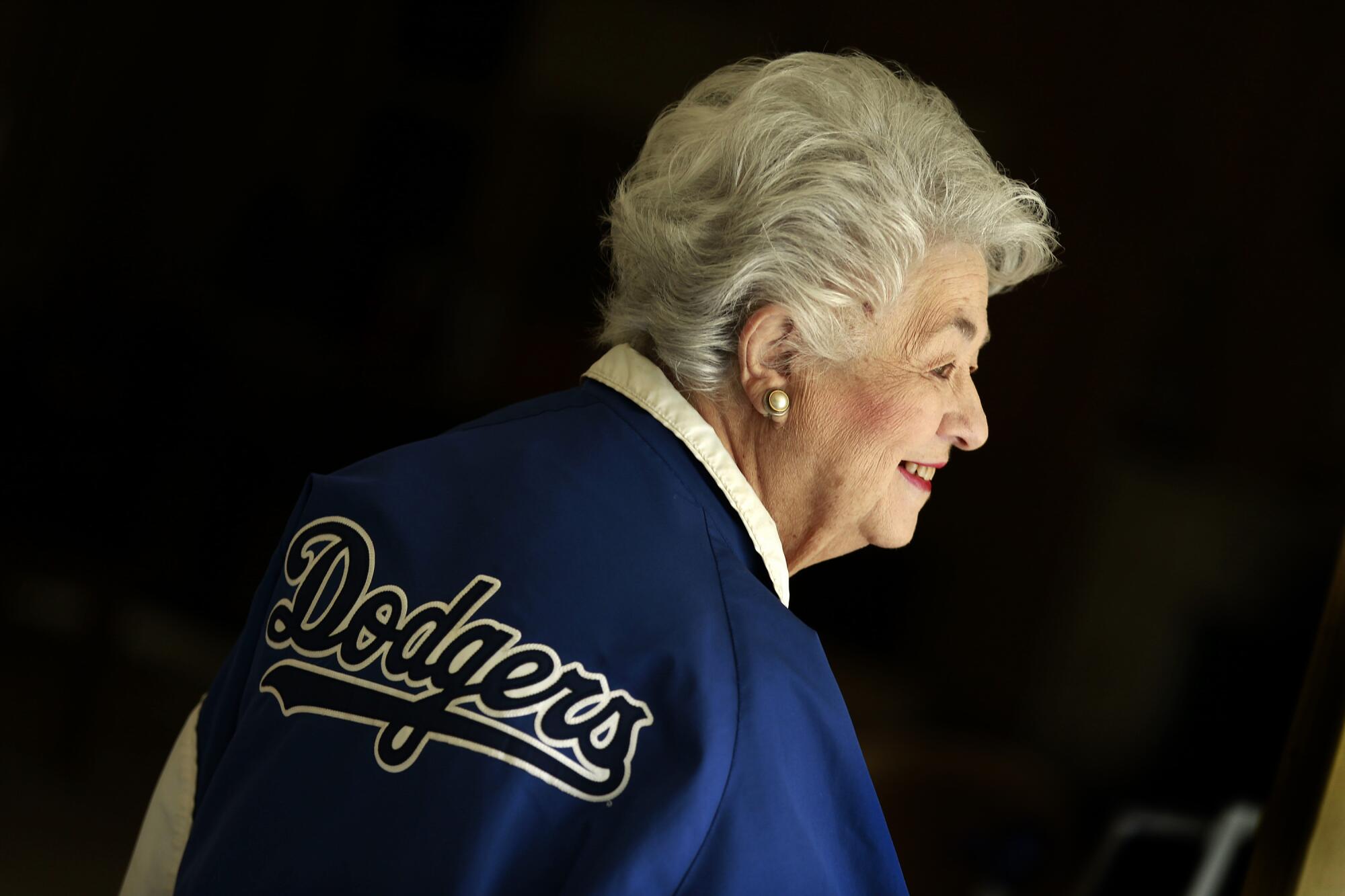 A white haired smiling woman wears a Dodgers jacket