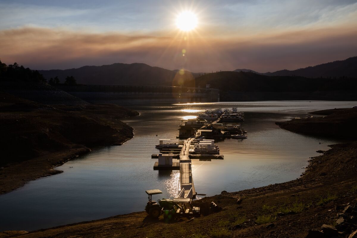 The Centimudi boat ramp sits on a receded Shasta Lake with Shasta Dam in the background.