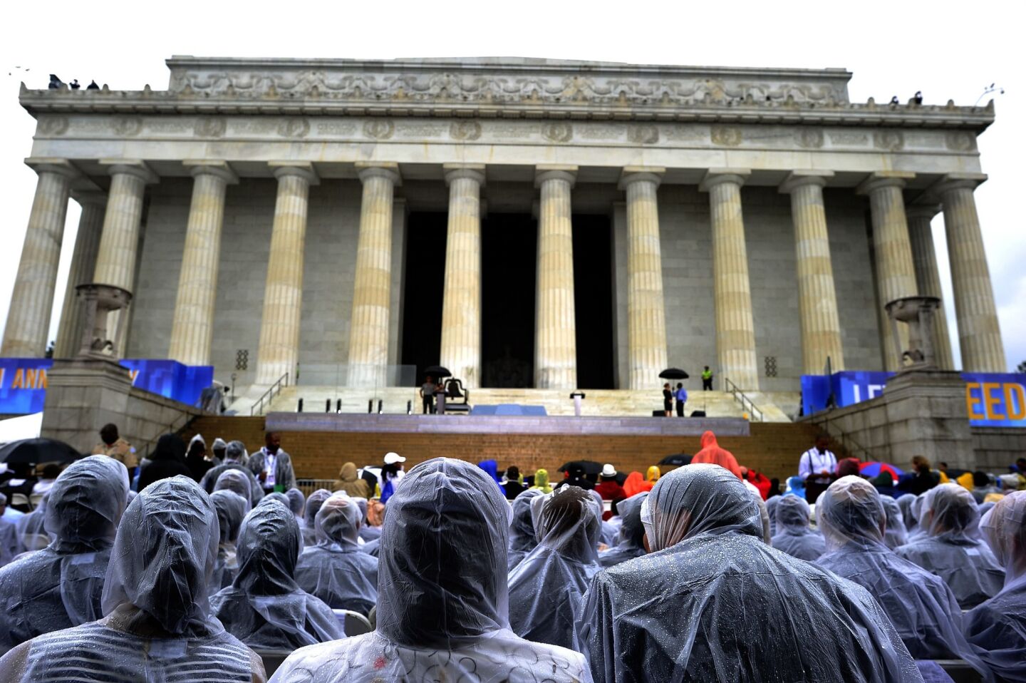 People cover themselves with rain ponchos in front of the Lincoln Memorial on the 50th anniversary of the March on Washington.