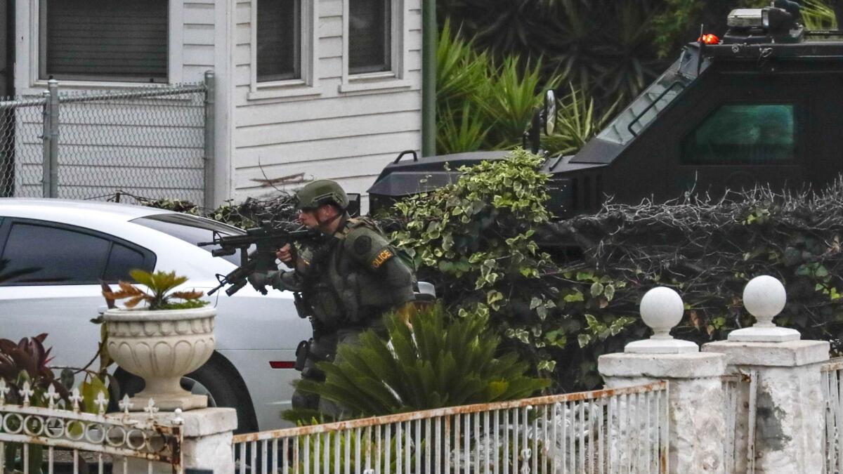 A Pomona police SWAT team enters a residence to clear it after exchanging gunfire with one of the occupants of a house Thursday morning while serving a search warrant on a suspected gang member during a multi-agency sweep in Azusa.