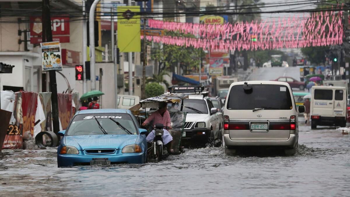 Vehicles navigate an area flooded by rains from Typhoon Nock-Ten in Quezon, Philippines, on Dec. 26.