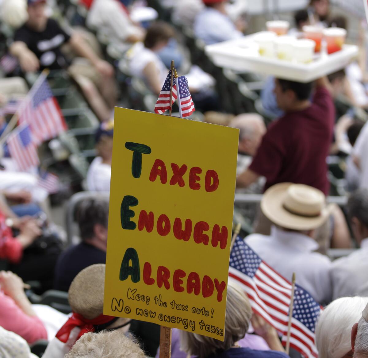 Activist in a crowd with a sign that says "taxed enough already"
