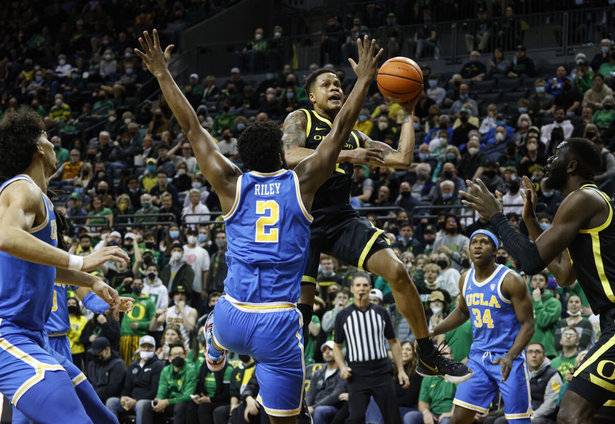 Oregon guard Jacob Young, center right, shoots against UCLA forward Cody Riley.