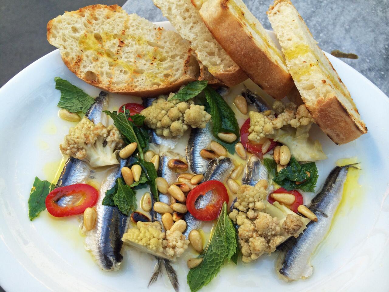 A plate of anchovies, pine nuts, chiles, pickled Romenesco, mint and grilled bread ($6).