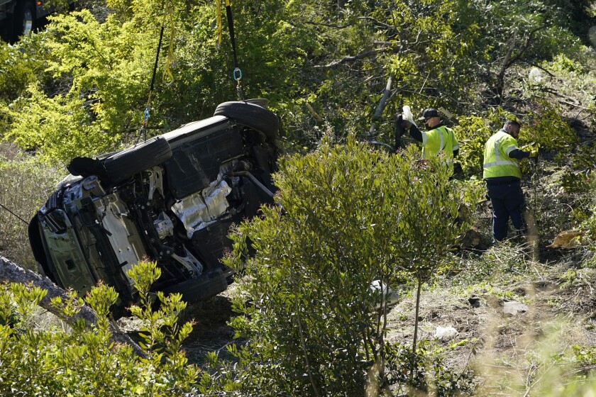 Workers collect debris beside a vehicle after a rollover accident involving golfer Tiger Woods Tuesday, Feb. 23, 2021, in Rancho Palos Verdes, Calif., a suburb of Los Angeles. Woods suffered leg injuries in the one-car accident and was undergoing surgery, authorities and his manager said. (AP Photo/Marcio Jose Sanchez)