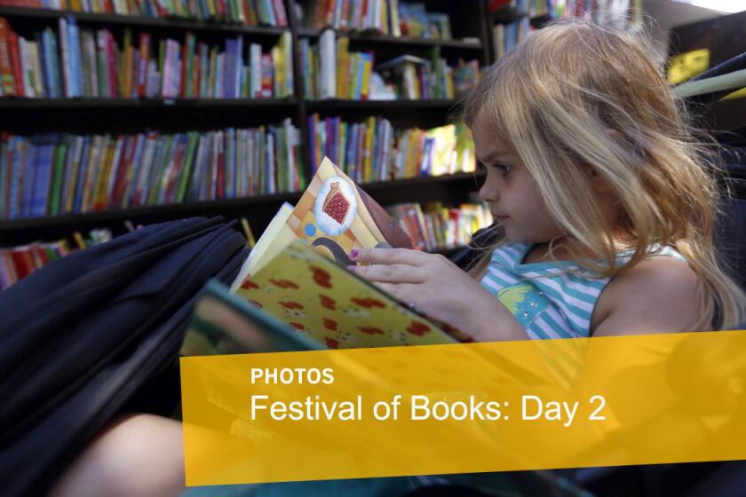 Lillian Larkins, 4, sits in her stroller and checks out a book at the 20th Los Angeles Times Festival of Books at USC on Sunday.