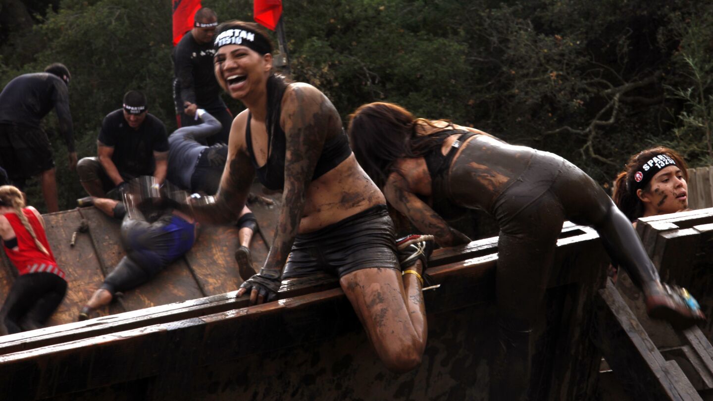 A woman laughs as she crosses over the "inverted wall" obstacle during the Spartan Race at Calamigos Ranch in Malibu on Dec. 7, 2014.
