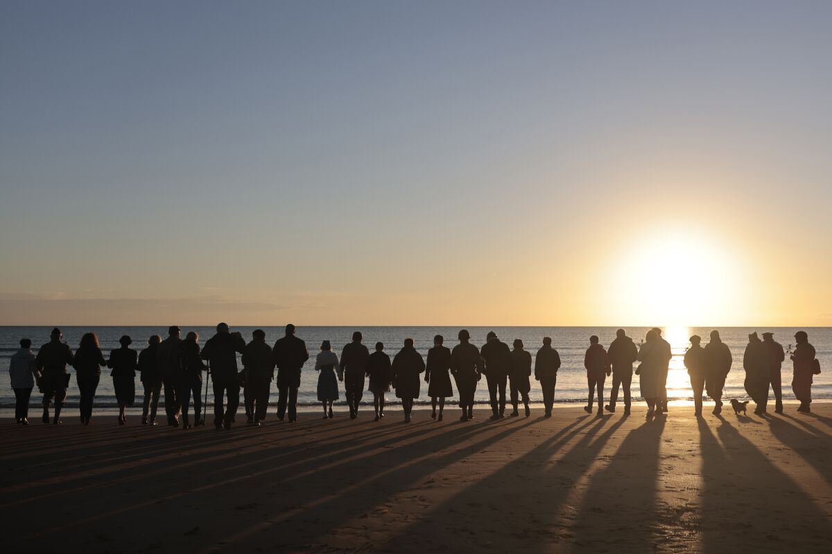 Silhouettes of people in a line on the beach