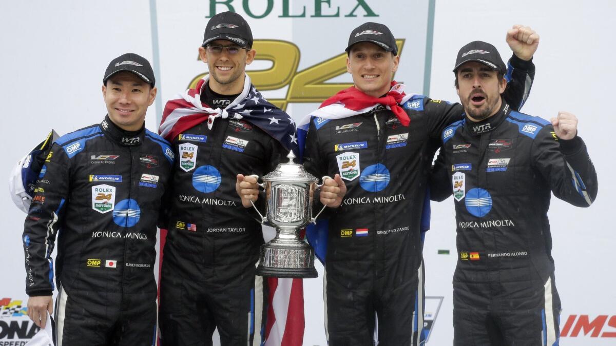 Winners of the IMSA 24 hour race, from left, Kamui Kobayashi, Jordan Taylor, Renger Van Der Zande, and Fernando Alonso celebrate with the championship trophy at Daytona International Speedway on Sunday.