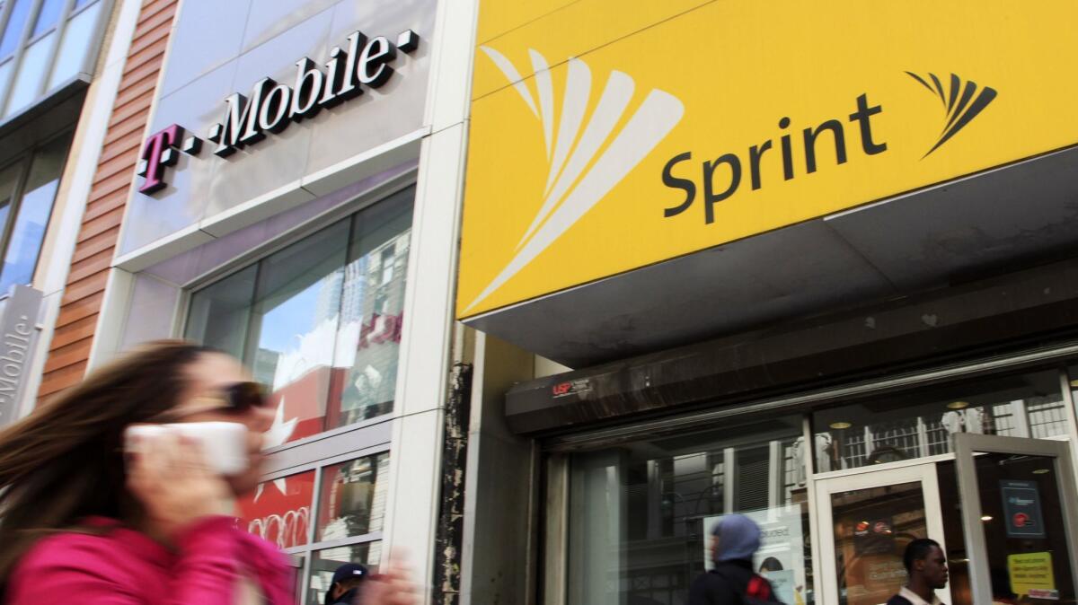 A woman using a cell phone walks past T-Mobile and Sprint stores in New York City on April 27, 2010.