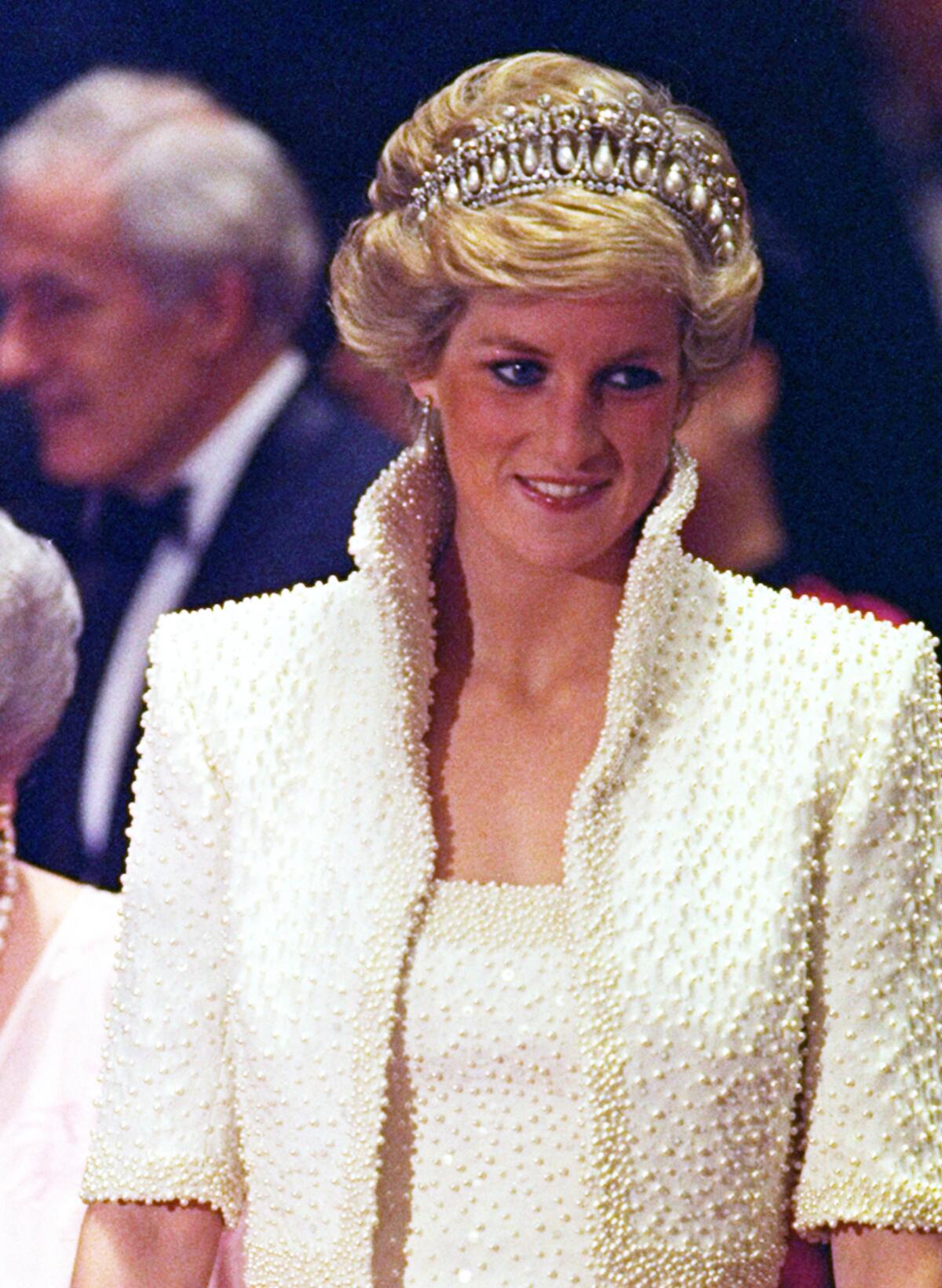 November 1989: Diana wears a beaded white gown and bolero she called her “Elvis dress.” It's by Catherine Walker.