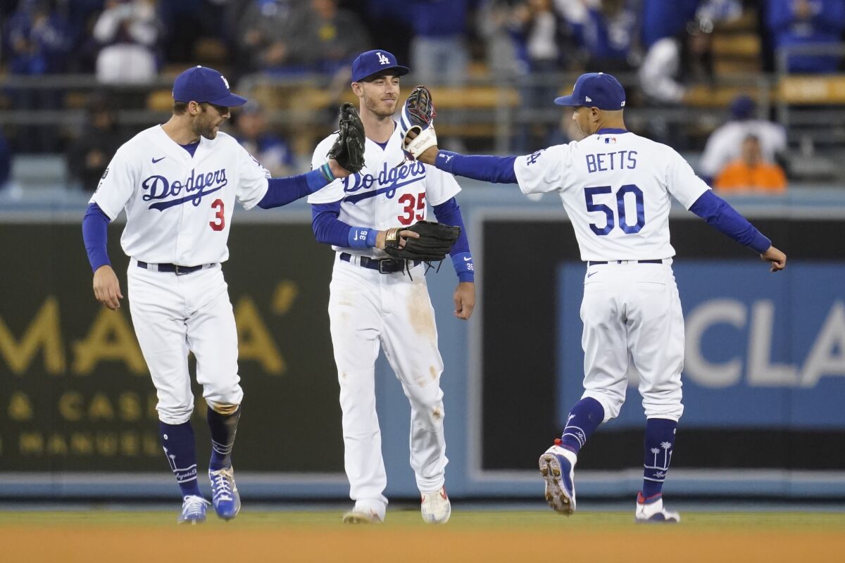 Los Angeles Dodgers' Chris Taylor (3), Cody Bellinger (35) and Mookie Betts (50) celebrate after the Dodgers defeated the San Francisco Giants 7-2 in Game 4 of a baseball National League Division Series, Tuesday, Oct. 12, 2021, in Los Angeles. (AP Photo/Ashley Landis)