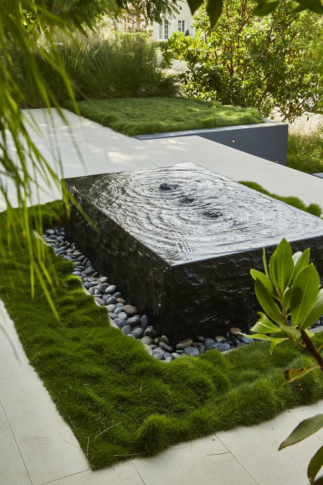 A soft carpet of Zoysia tenuifolia (Korean grass) frames a fountain. In addition to creating water music, the fountain invites birds to bathe in its shallow water.