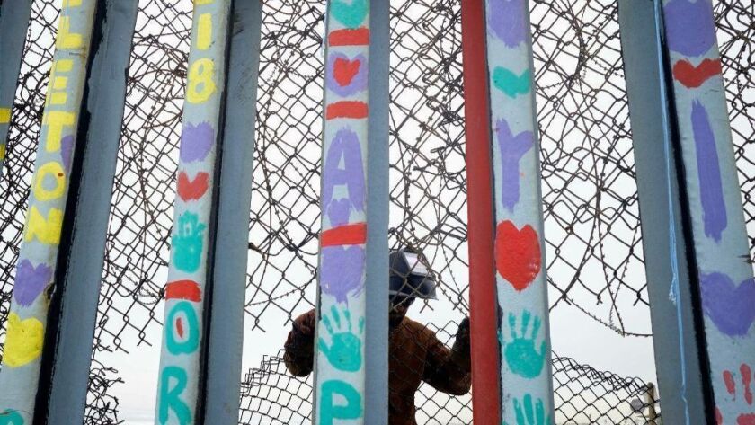 Fencing separating San Diego from Tijuana is replaced March 11 by a worker on the U.S. side.